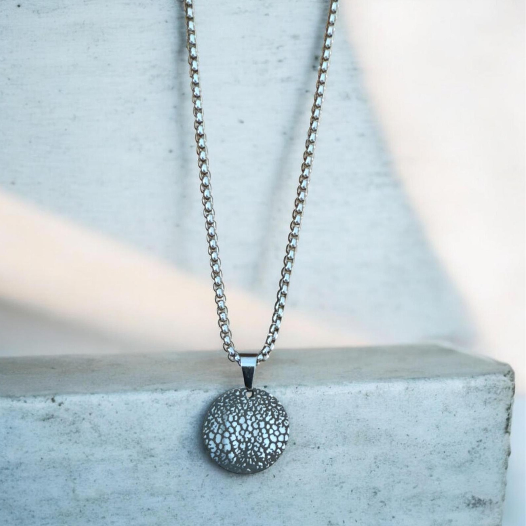 Round dog nose print pendent with chain. Grey background