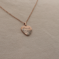 A rose gold heart pendant necklace engraved with the word 'Lavender' on a textured fabric background.